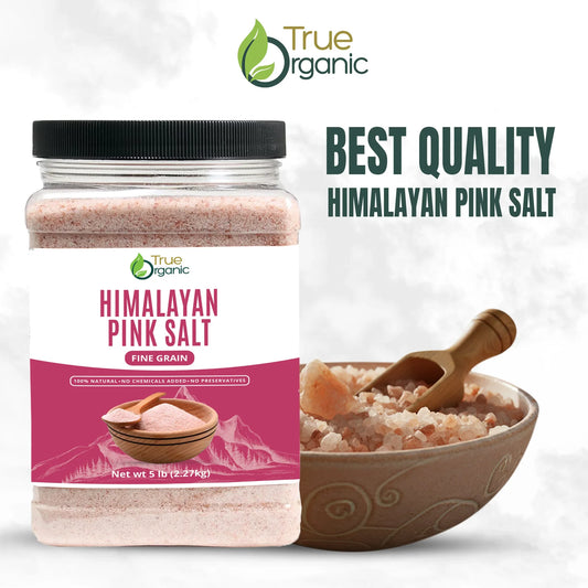 Container of True Organic Himalayan pink salt fine grain next to a bowl with coarse pink salt and wooden scoop
