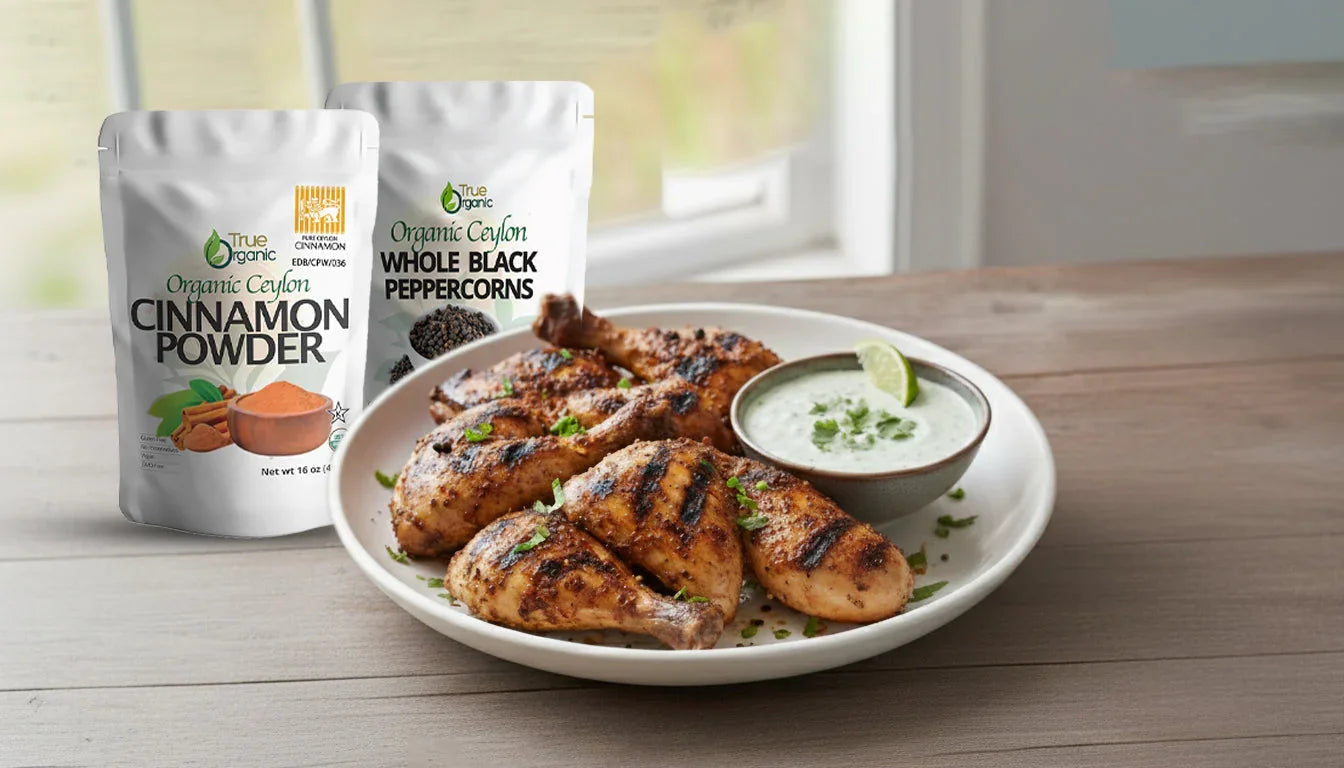 Grilled chicken drumsticks garnished with herbs on white plate with lime sauce and organic cinnamon powder and black peppercorns packets