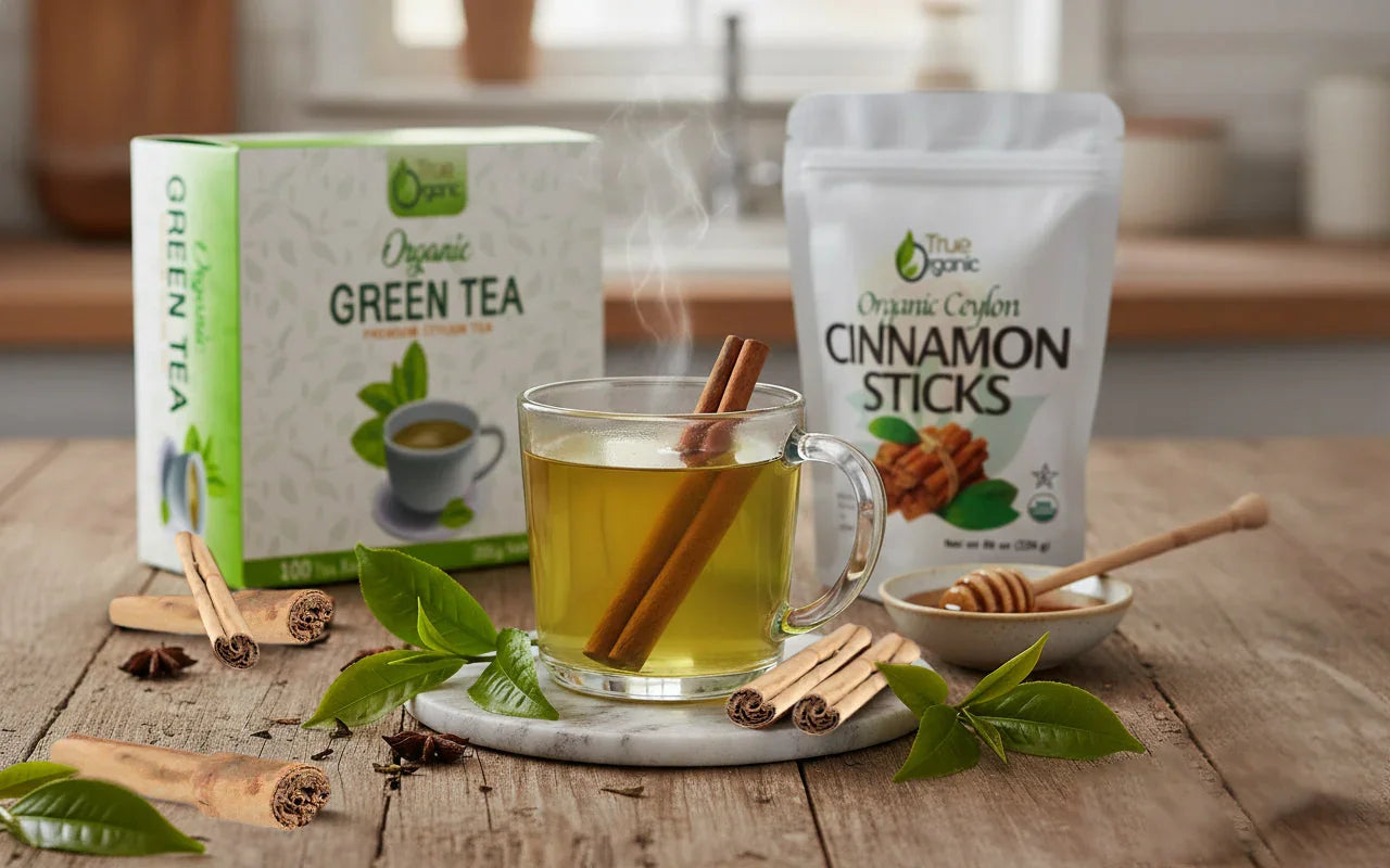 Steaming cup of green tea with cinnamon sticks, organic green tea box, cinnamon stick pack, honey dipper on wooden table