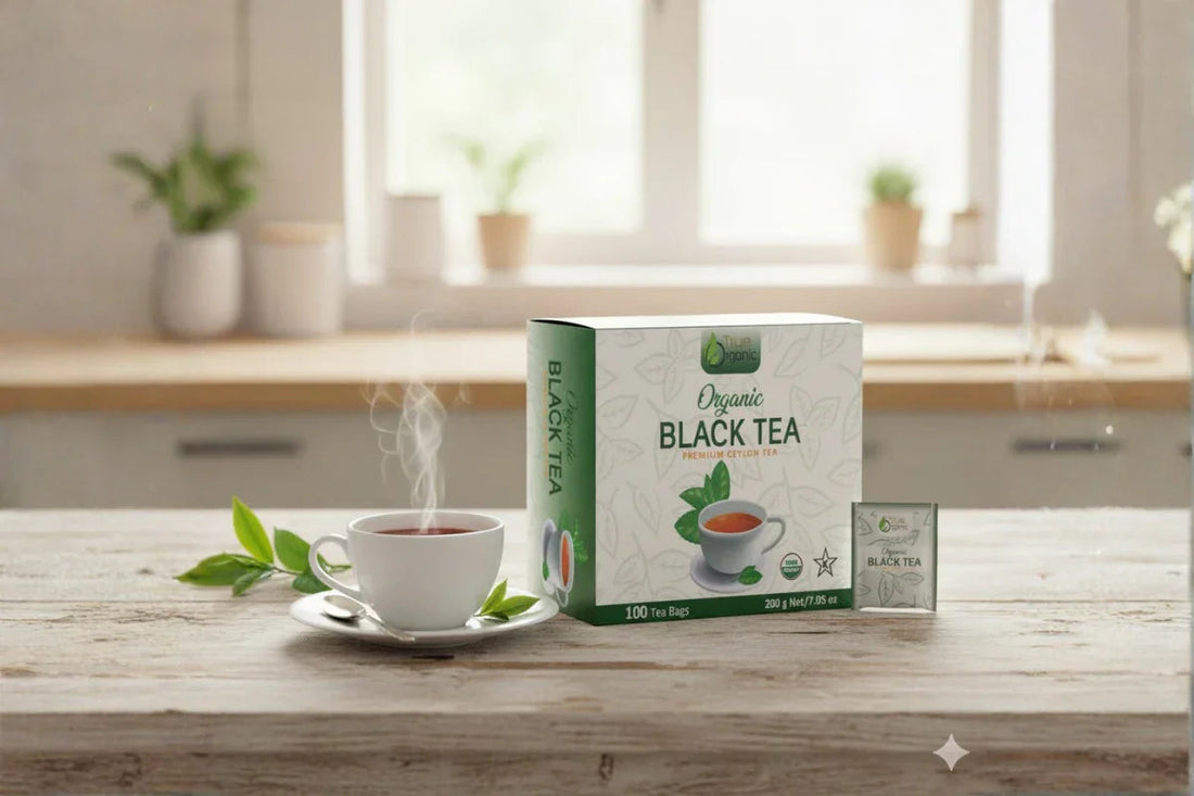 Steaming cup of black tea on saucer with box of organic black tea bags on wooden table in bright kitchen