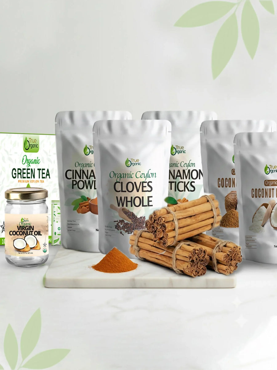 Organic Ceylon spices collection with cinnamon sticks, whole cloves, cinnamon powder, virgin coconut oil, and green tea on white marble