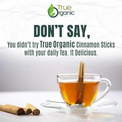 Glass cup of tea with True Organic cinnamon stick, cinnamon sticks nearby, True Organics branding.