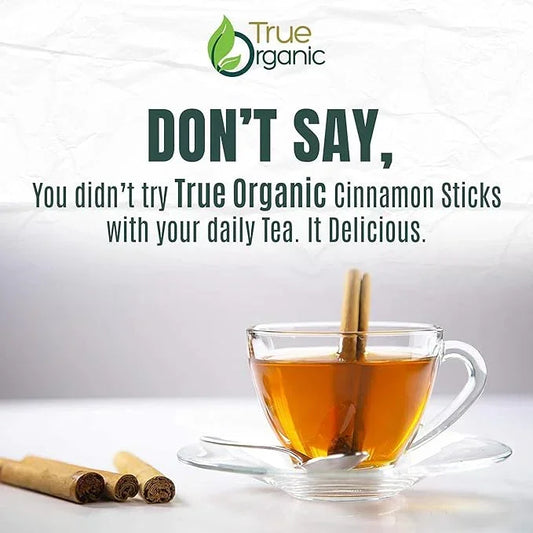 Glass cup of tea with True Organic cinnamon stick, cinnamon sticks nearby, True Organics branding.
