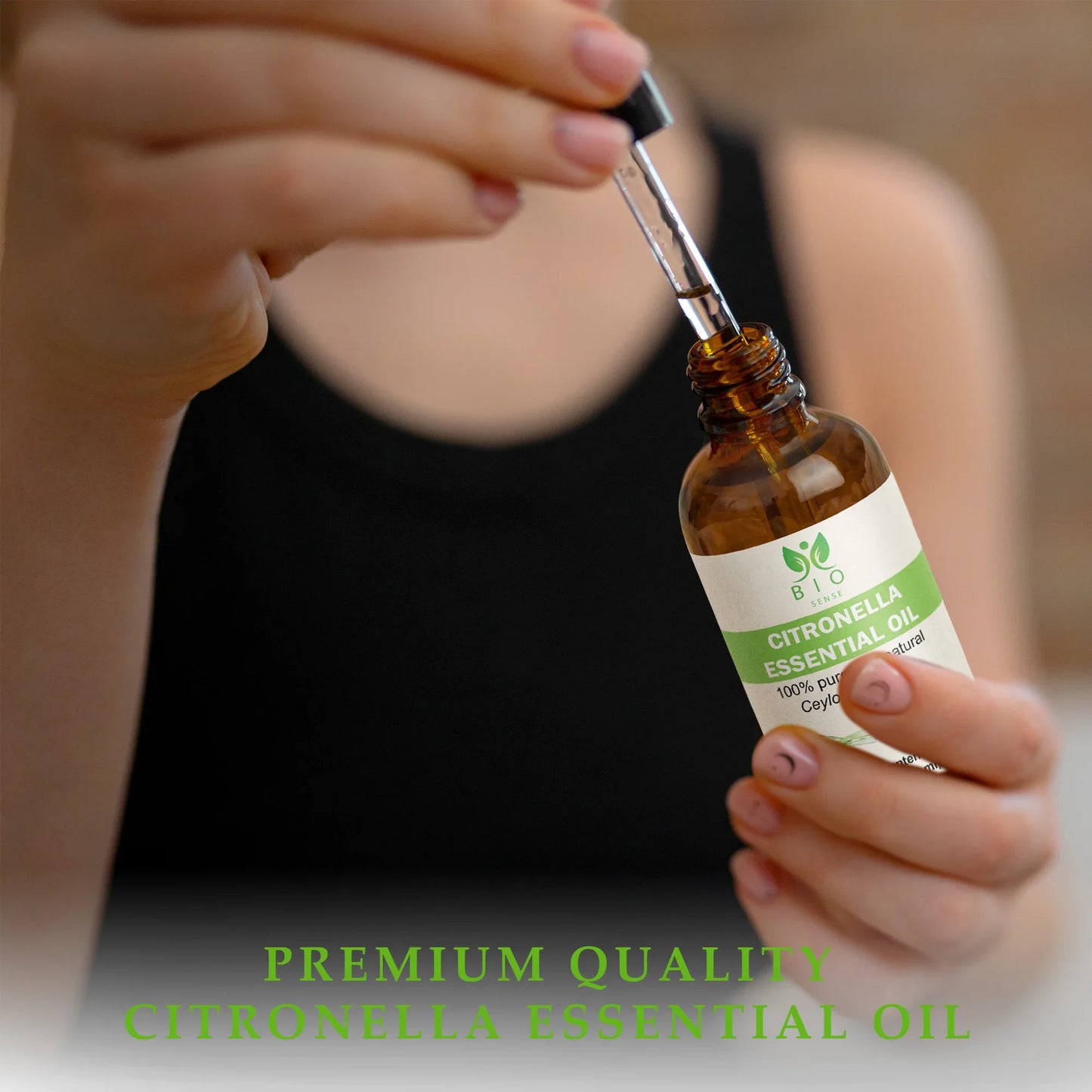 Person holding dropper and amber bottle of Bio Sense Citronella Essential Oil