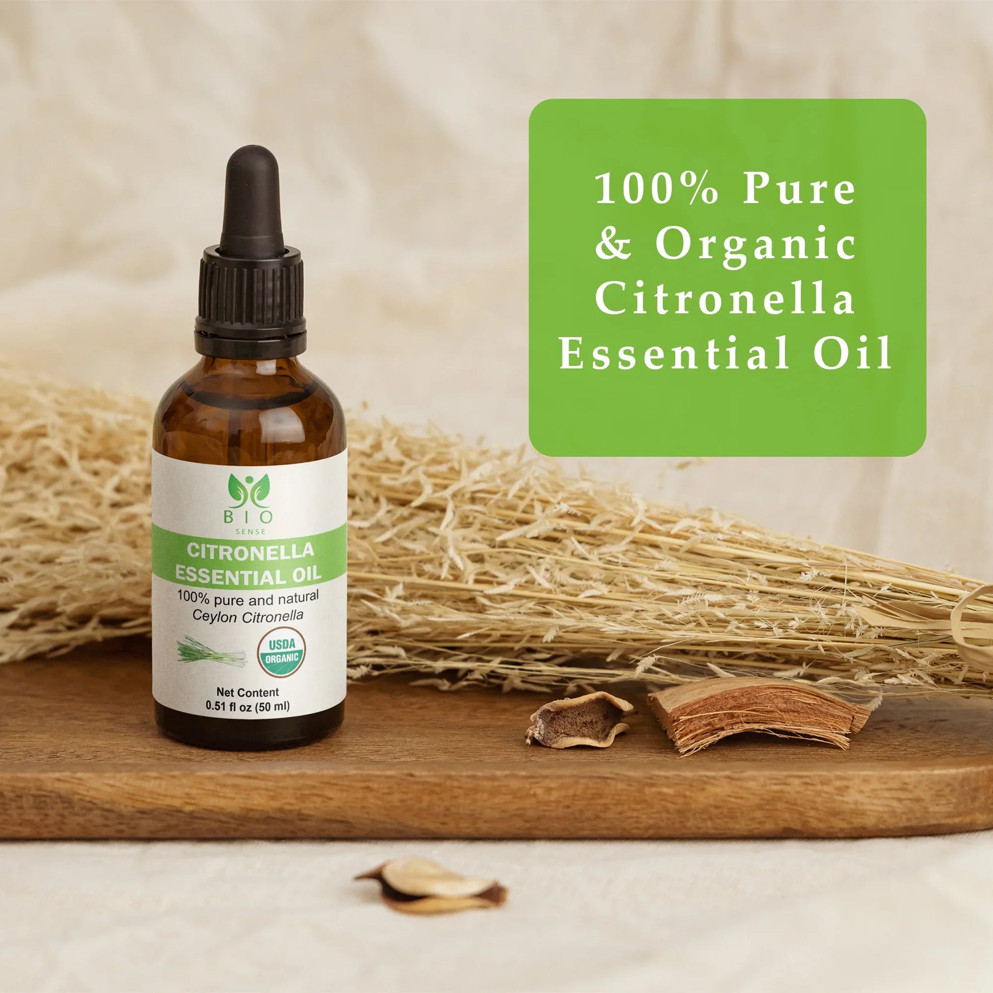 Amber bottle of 100% pure organic citronella essential oil on wooden tray with dried plants