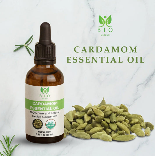 Bio Sense cardamom essential oil bottle next to green cardamom pods on marble background