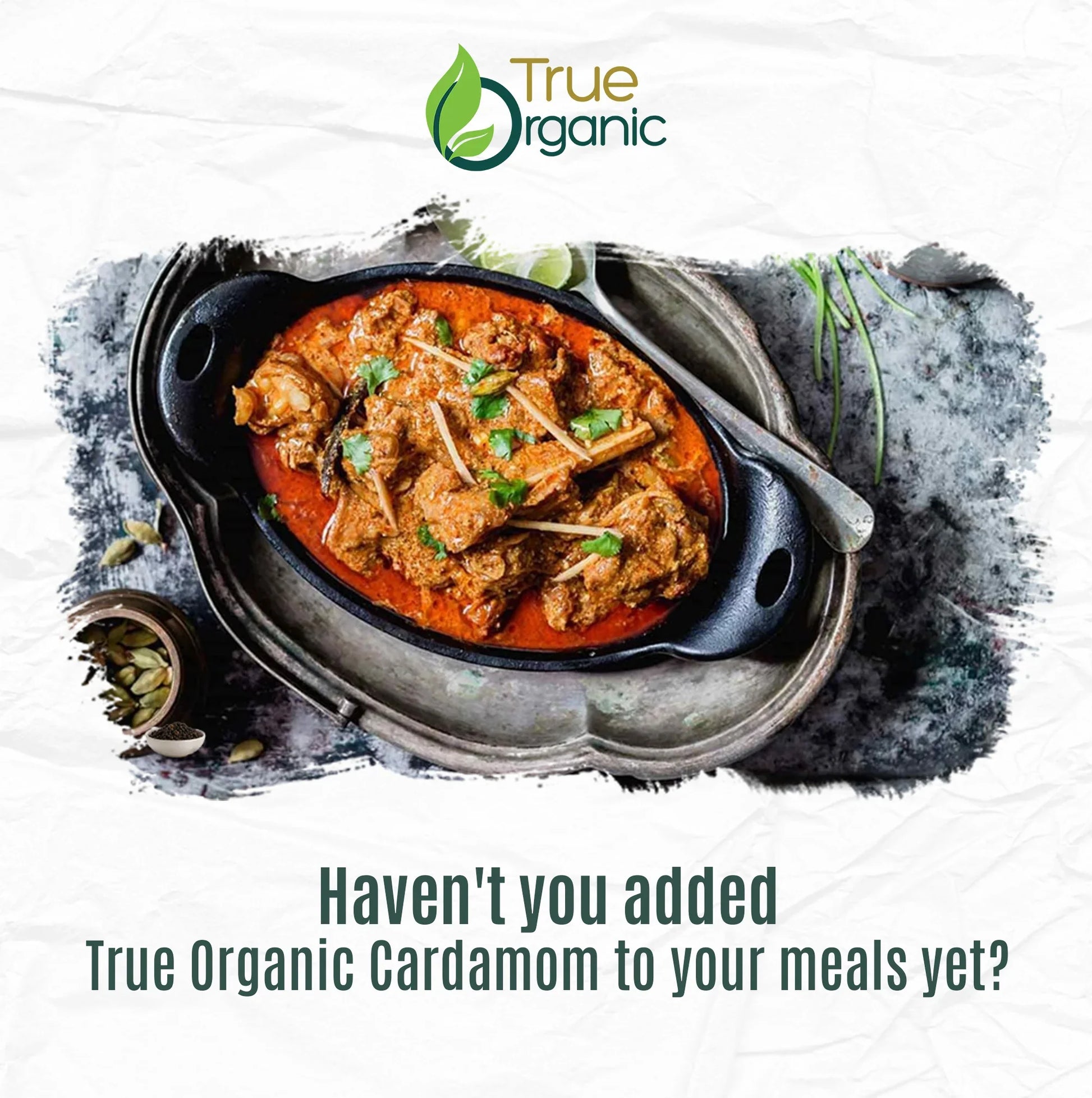 True Organic cardamom curry in black dish with spoon on rustic tray, garnished with herbs