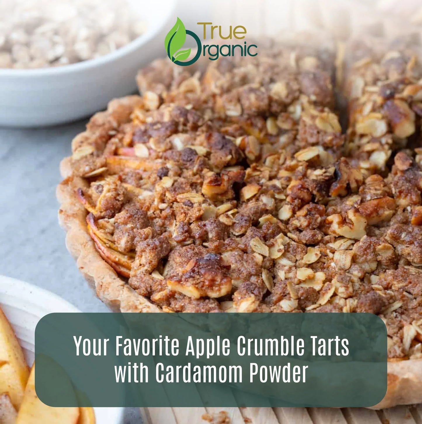 Close-up of apple crumble tart with oat and nut topping, featuring cardamom powder branding