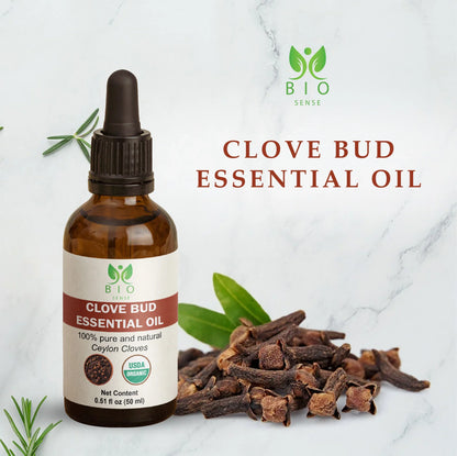 Bio Sense clove bud essential oil bottle with dried cloves and green leaves on marble background