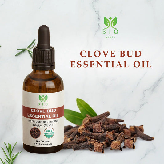 Bio Sense clove bud essential oil bottle with dried cloves and green leaves on marble background