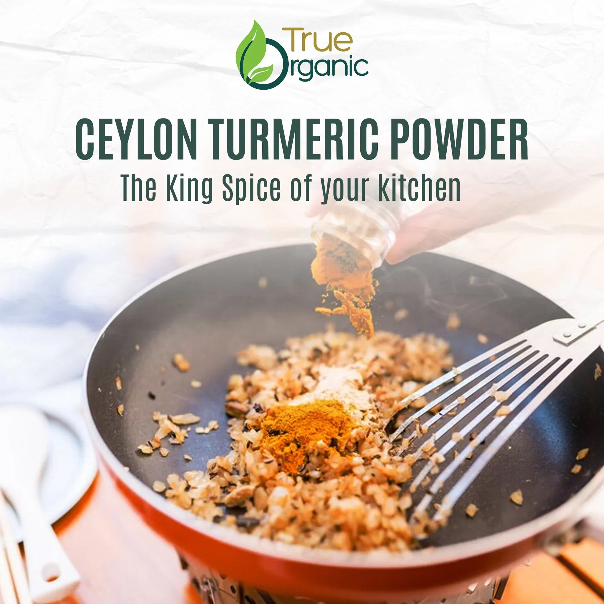 Hand sprinkling Ceylon turmeric powder into a pan with sautéed onions, metal spatula visible