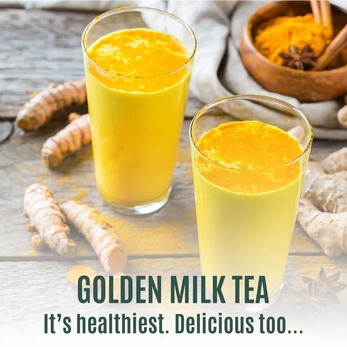 Two glasses of golden milk tea with turmeric powder and fresh turmeric on wooden table