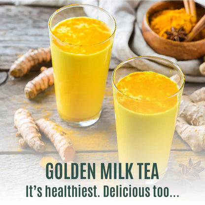 Two glasses of golden milk tea with turmeric powder and fresh turmeric on wooden table